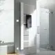 Vertikaler Kermi-Heizkörper in Weiß mit Längsrippen und Handtuchhalter, montiert an der Wand neben einer Glasdusche und einer Badewanne.